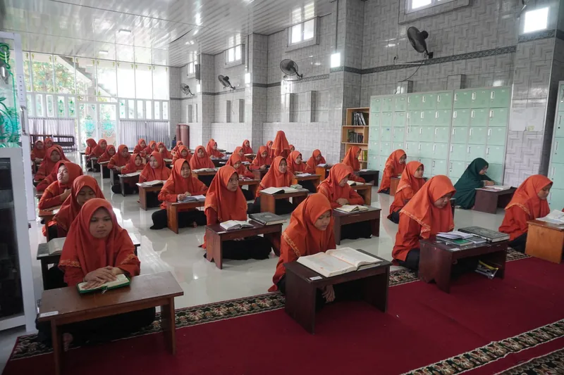 Santri berjilbab oranye mengikuti kegiatan belajar dan murojaah bersama di ruang kelas